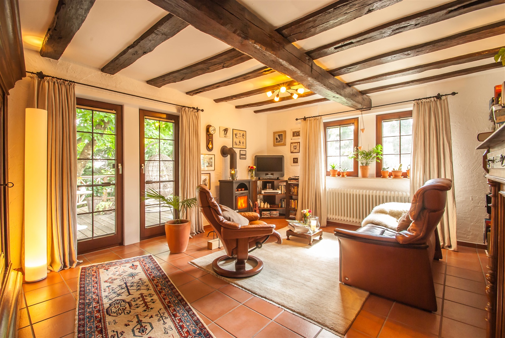 Wohnzimmer mit Holzofen und doppelflügliger Fenstertür zur neuwertigen Holzdielenterrasse - Oliver Reifferscheid - Immobilienmakler Darmstadt
